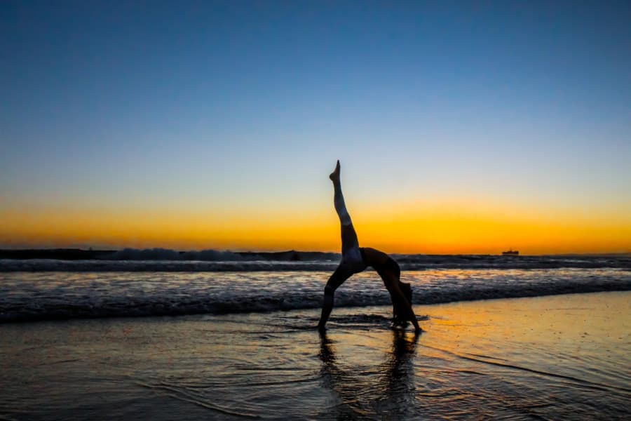 Flexible person doing yoga on the beach