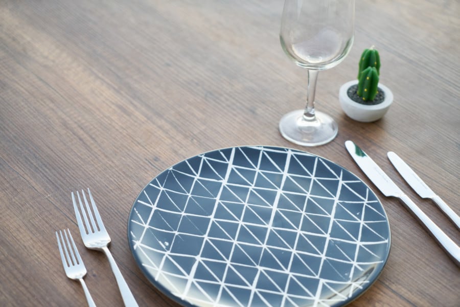 Round Blue and White Ceramic Plate, Two Forks, Two Knives, and Wine Glass